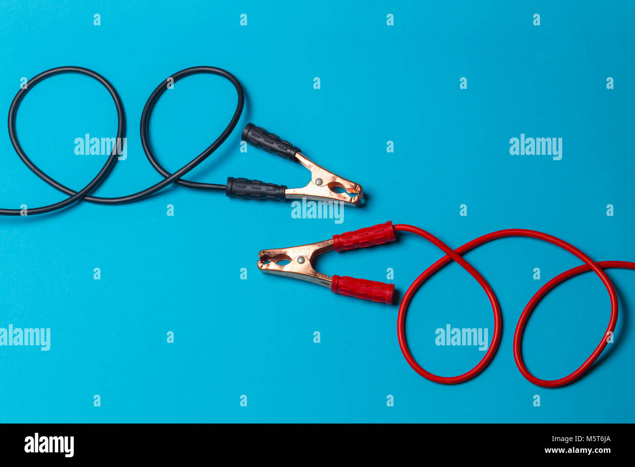 battery jumper cables on light blue background, red and black are