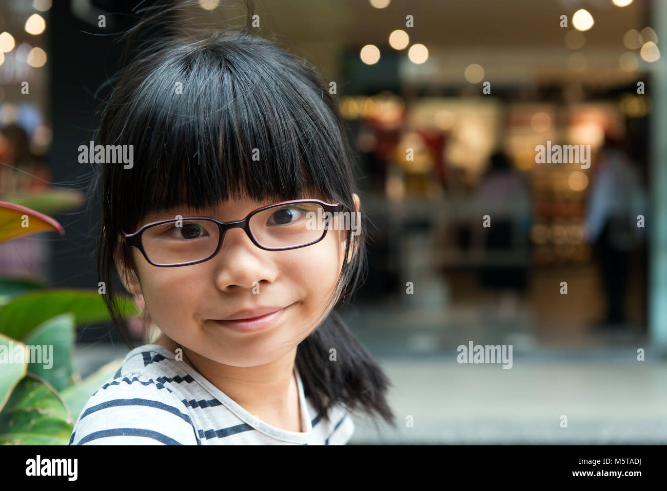 Cute Asian Chinese girl with glasses in park Stock Photo