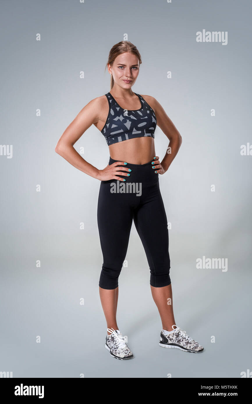 Young woman with beautiful slim healthy body posing in studio. Fitness  female model in sportswear looking at the camera on grey background Stock  Photo - Alamy