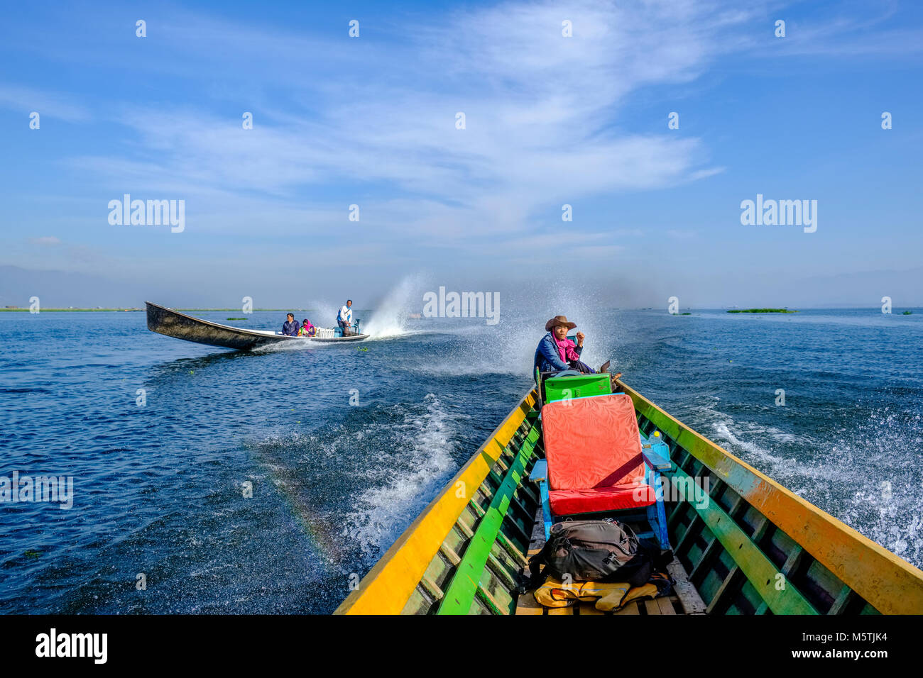 A motorboat is overtaking another on with full speed, driving on Inle lake Stock Photo