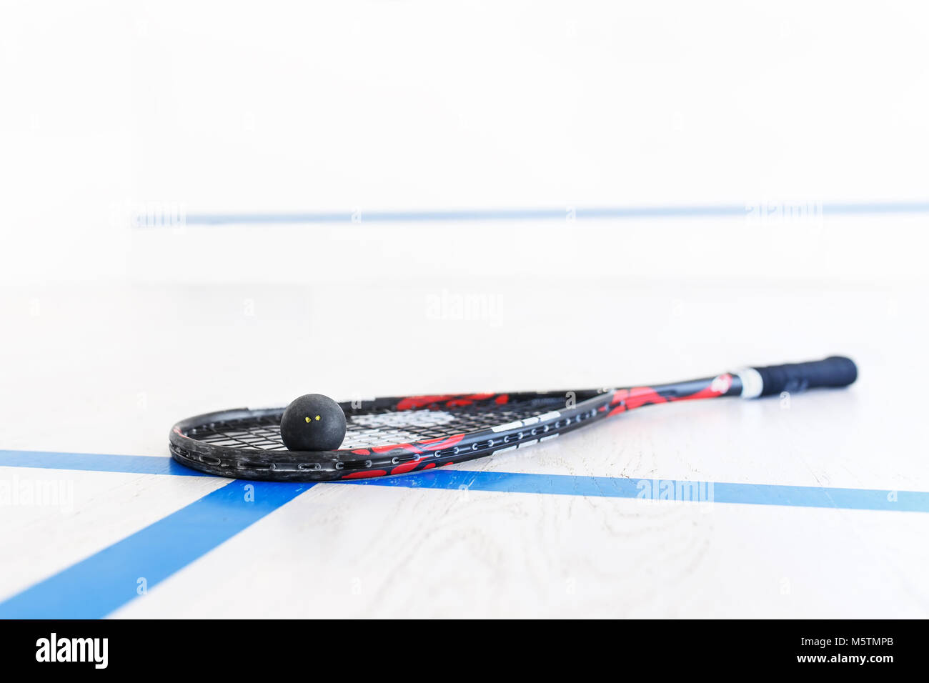 squash racket and ball on the wooden floor. Racquetball equipment on