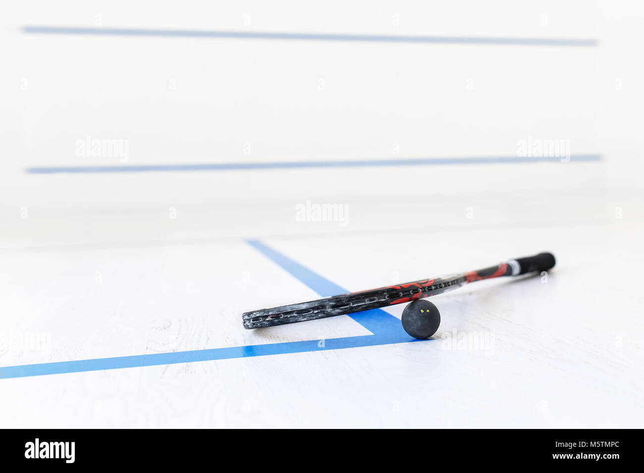 squash racket and ball on the wooden floor. Racquetball equipment on