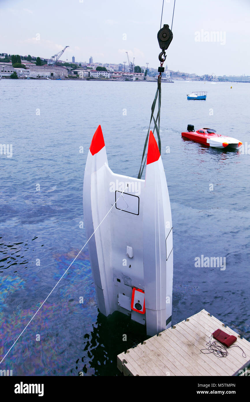 An offshore boat is pulled up by a crane after an accident in the race