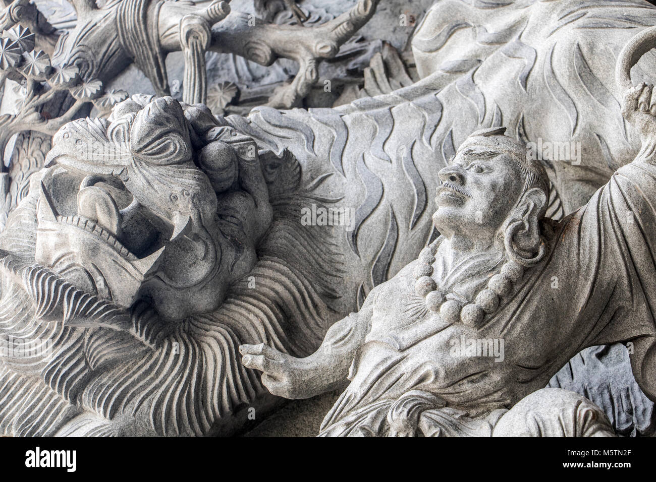 The mythology scene with stone tiger as a decoration on the facade of the Chinese monastery. Stock Photo