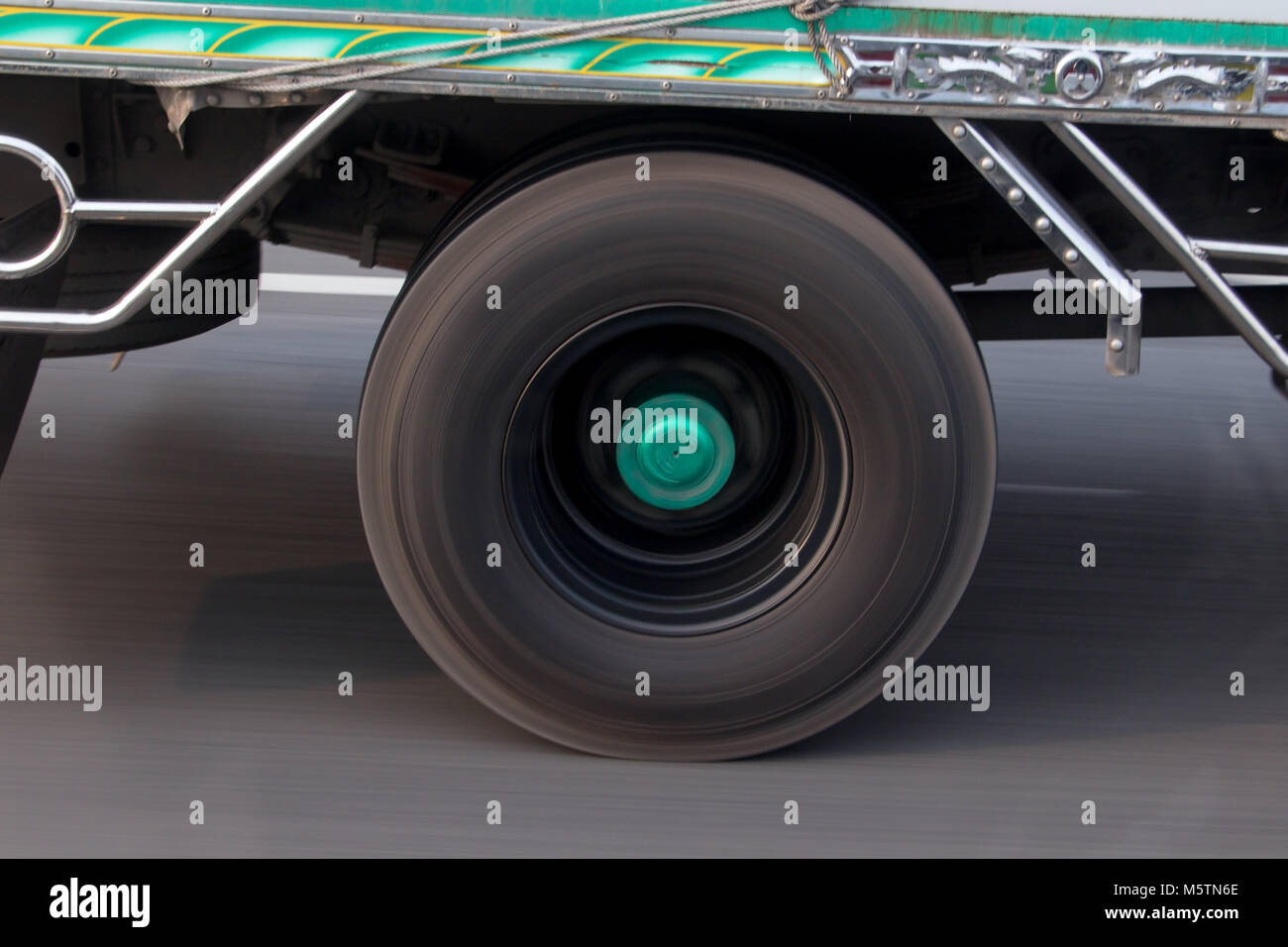 A spinning wheel of a truck running on the road. Detail of a rotating wheel of a truck. Stock Photo