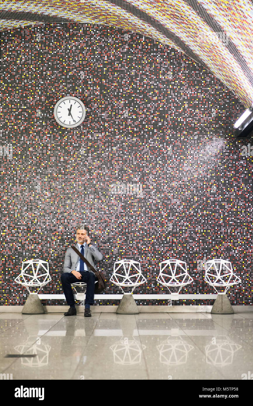 Mature businessman with smartphone in a metro station. Stock Photo