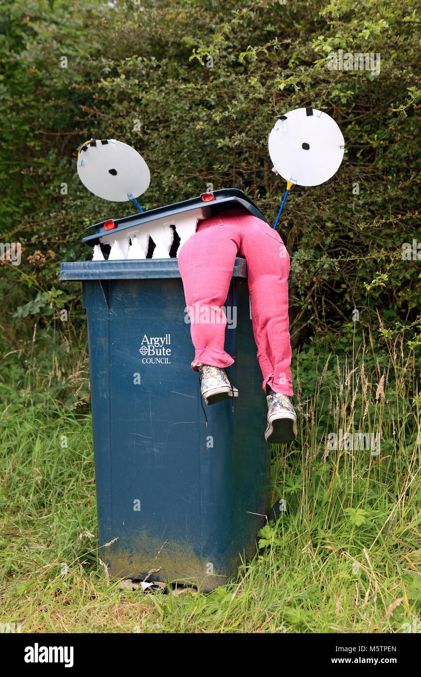 Legs hanging out of a wheelie bin which has been decorated as a monster