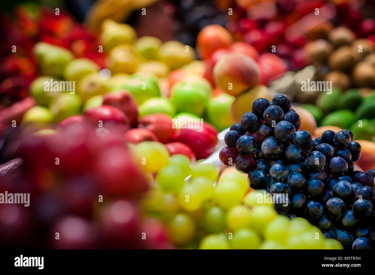 Piles of fruits (wine grapes, red and green apples, peaches etc.) are