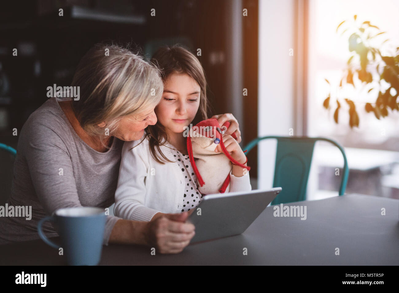 A small girl and grandmother with tablet at home Stock Photo - Alamy