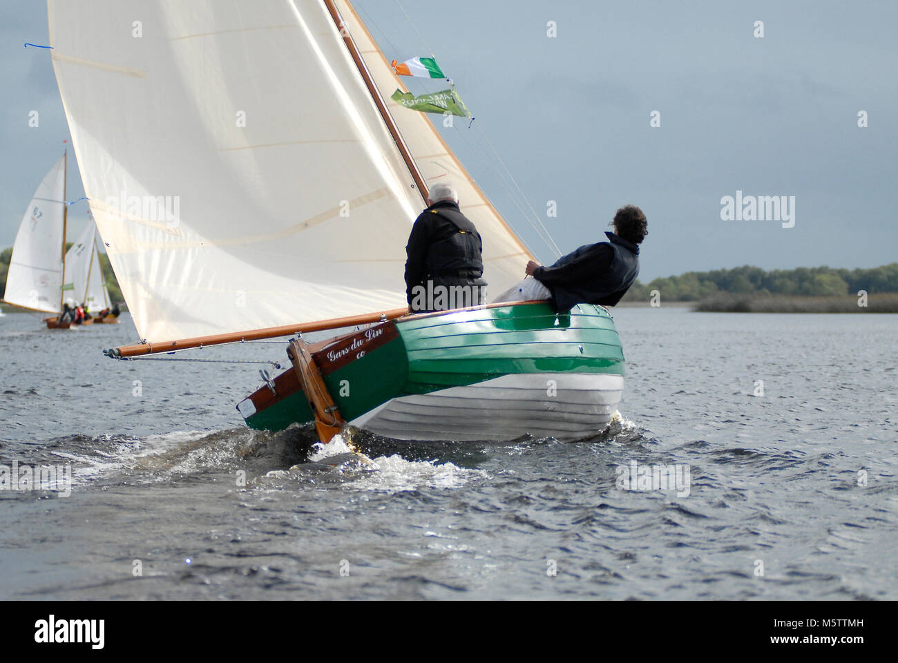 Sailing boat racing towards Tarmonbarry during a sailing raid on the River Shannon in Ireland. French sailor Patrick Morvan is at the helm. Stock Photo