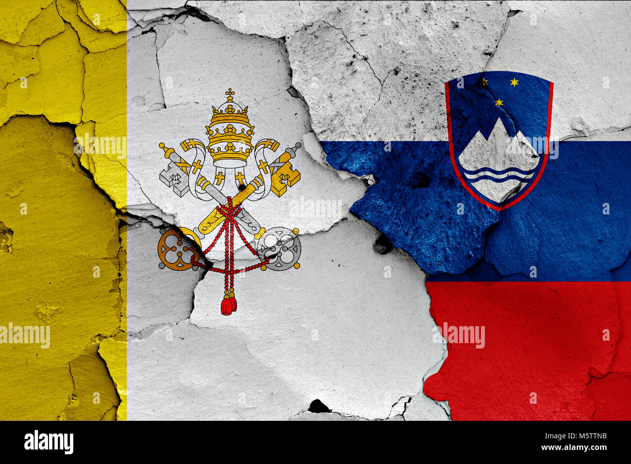 flag of Vatican and Slovenia painted on cracked wall Stock Photo