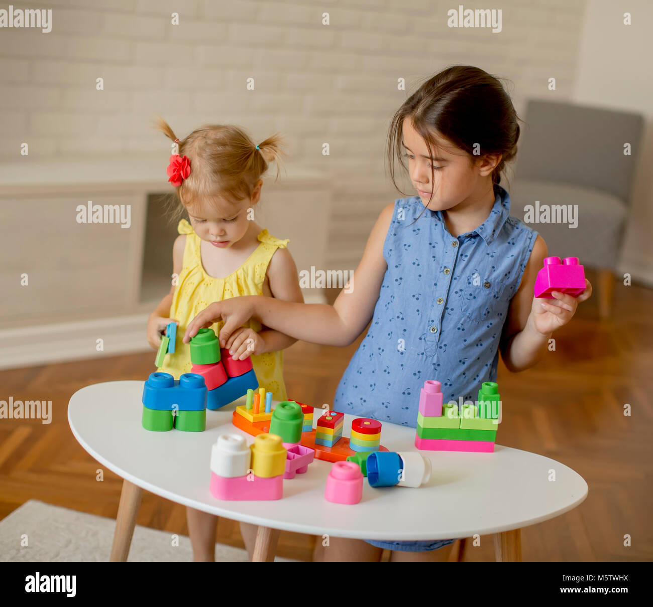 Two little girls play with cubes in the room Stock Photo - Alamy