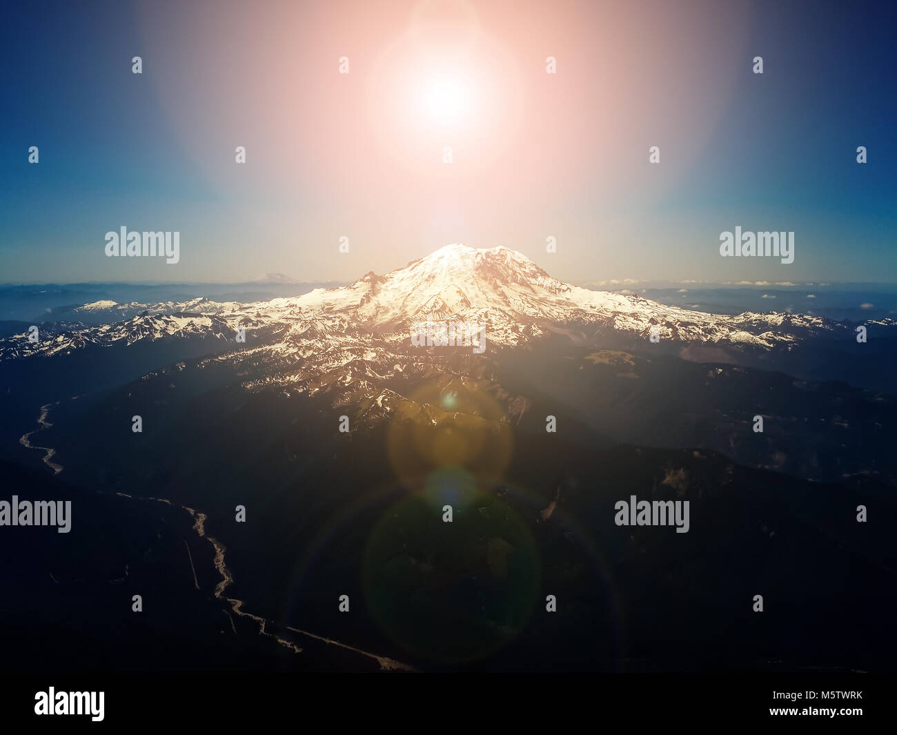 Bright sun in sky above mountain peak - aerial overhead view Stock Photo
