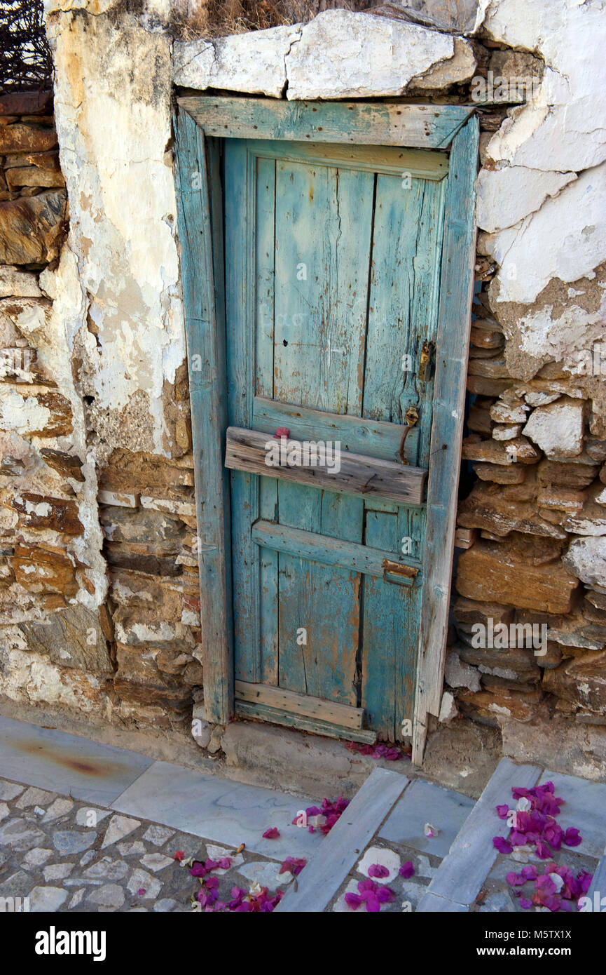 Dilapidated wooden doorway and bourgainvillea flowers in Syros, Greece. Stock Photo