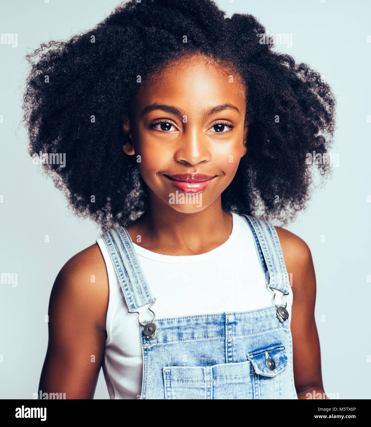 Cute young African girl with long curly hair smiling confidently and ...
