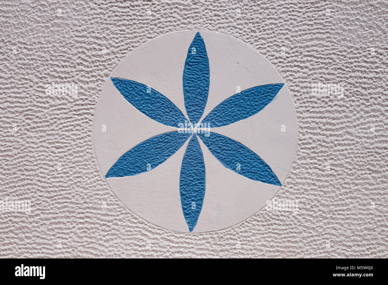 Painted blue flower on a white textured wall Stock Photo