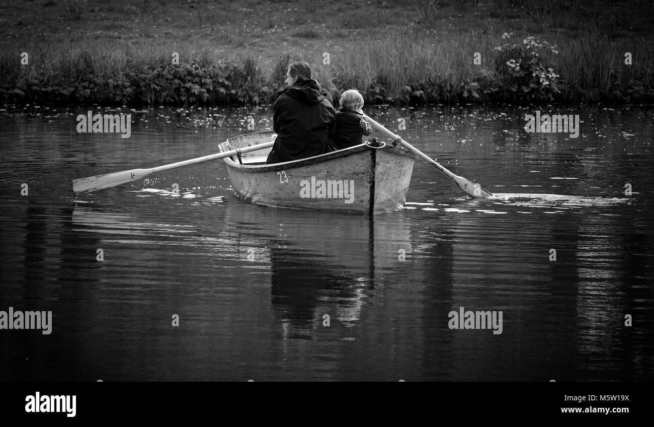 Father and son rowing a boat together on a lake Stock Photo