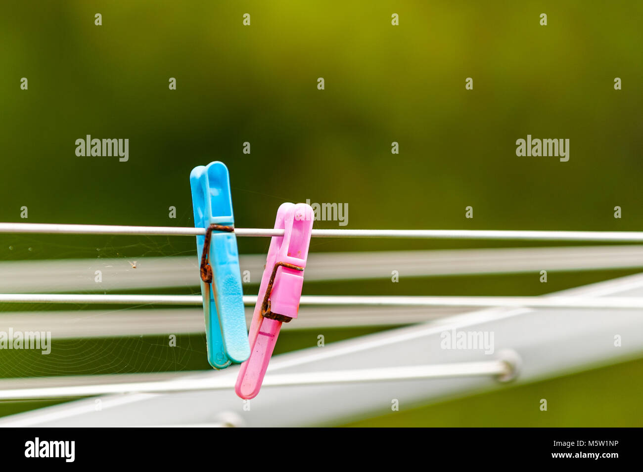 Two old broken plastic clothes pegs with rusty metal on a rotary washing line with bokeh and copy space. Stock Photo