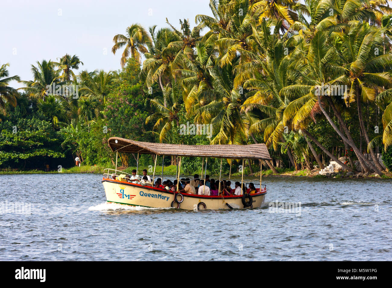 Passengers on a small boat crossing one of the many canals on the backwaters near Alleppy and Kumarakom in Kerala, India. Stock Photo