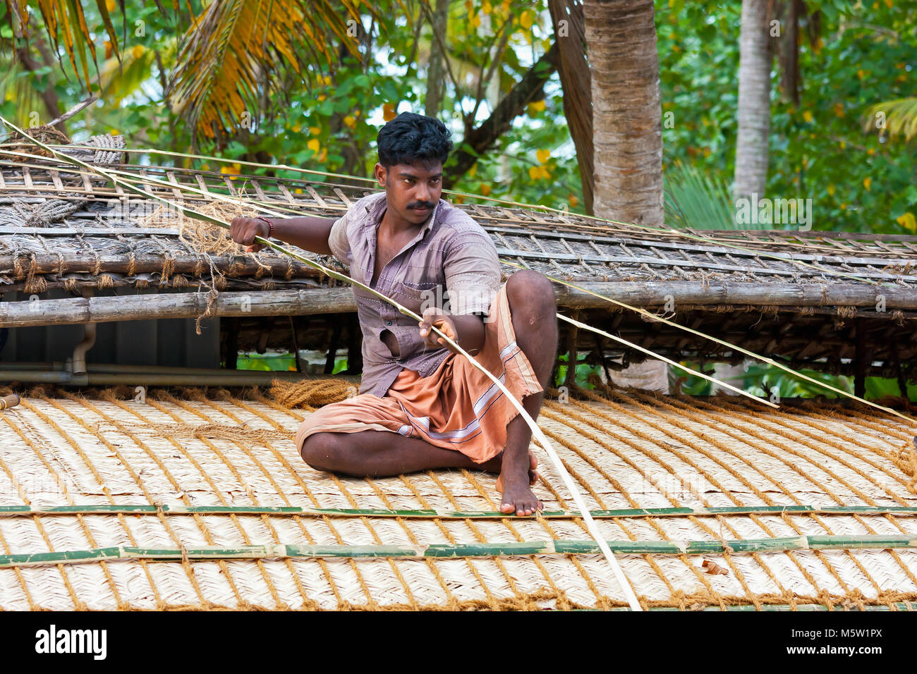 Repairing the roof of a houseboat (rice barge) on the backwaters near Alleppey and Kumarakom in Kerala, India. Stock Photo