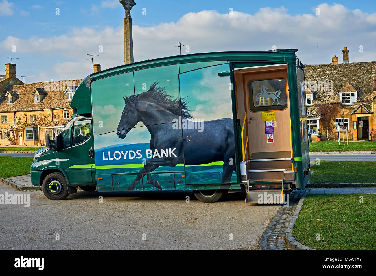 Mobile banking from Lloyds Bank on the High Street in the Cotswolds town of Broadway. Stock Photo