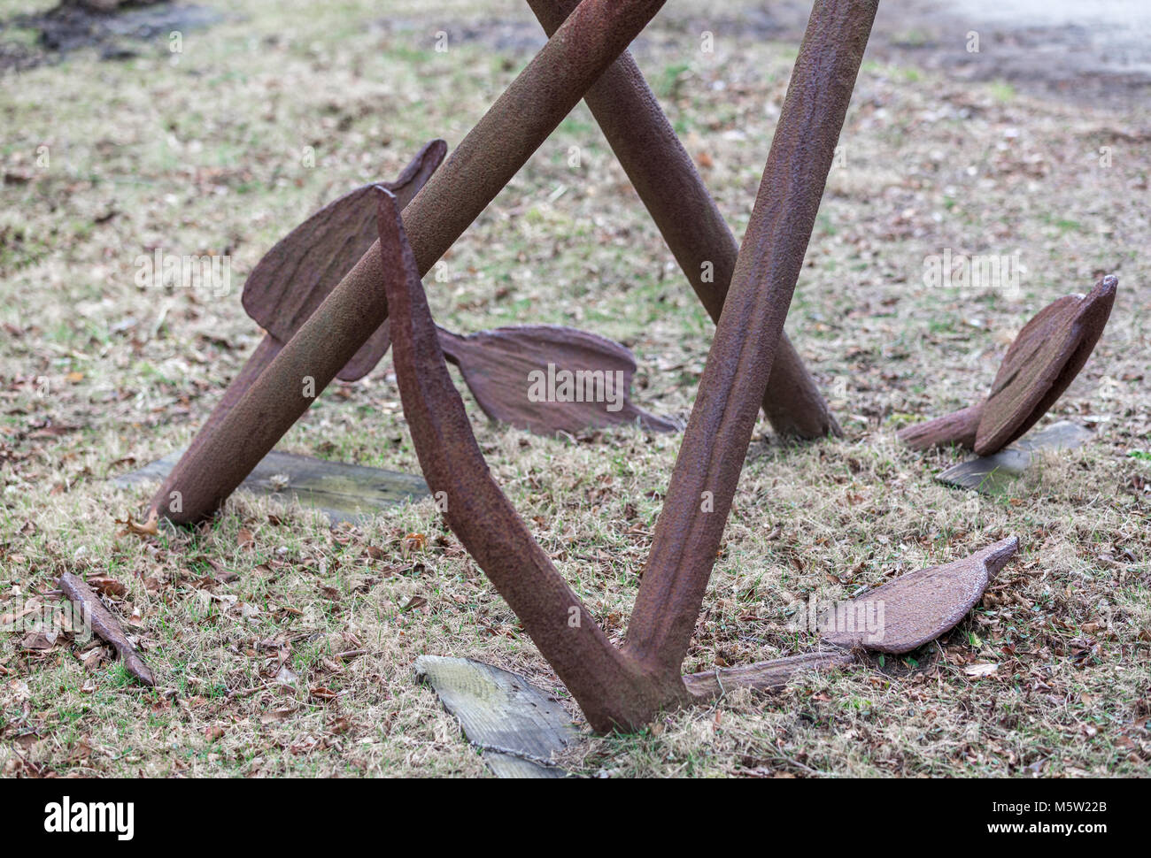 detail of three rusted anchors partially in the ground Stock Photo