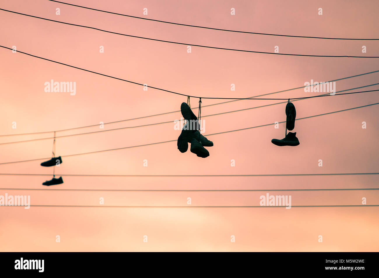 a silhouette of shoes having from telephone lines/cables during the day