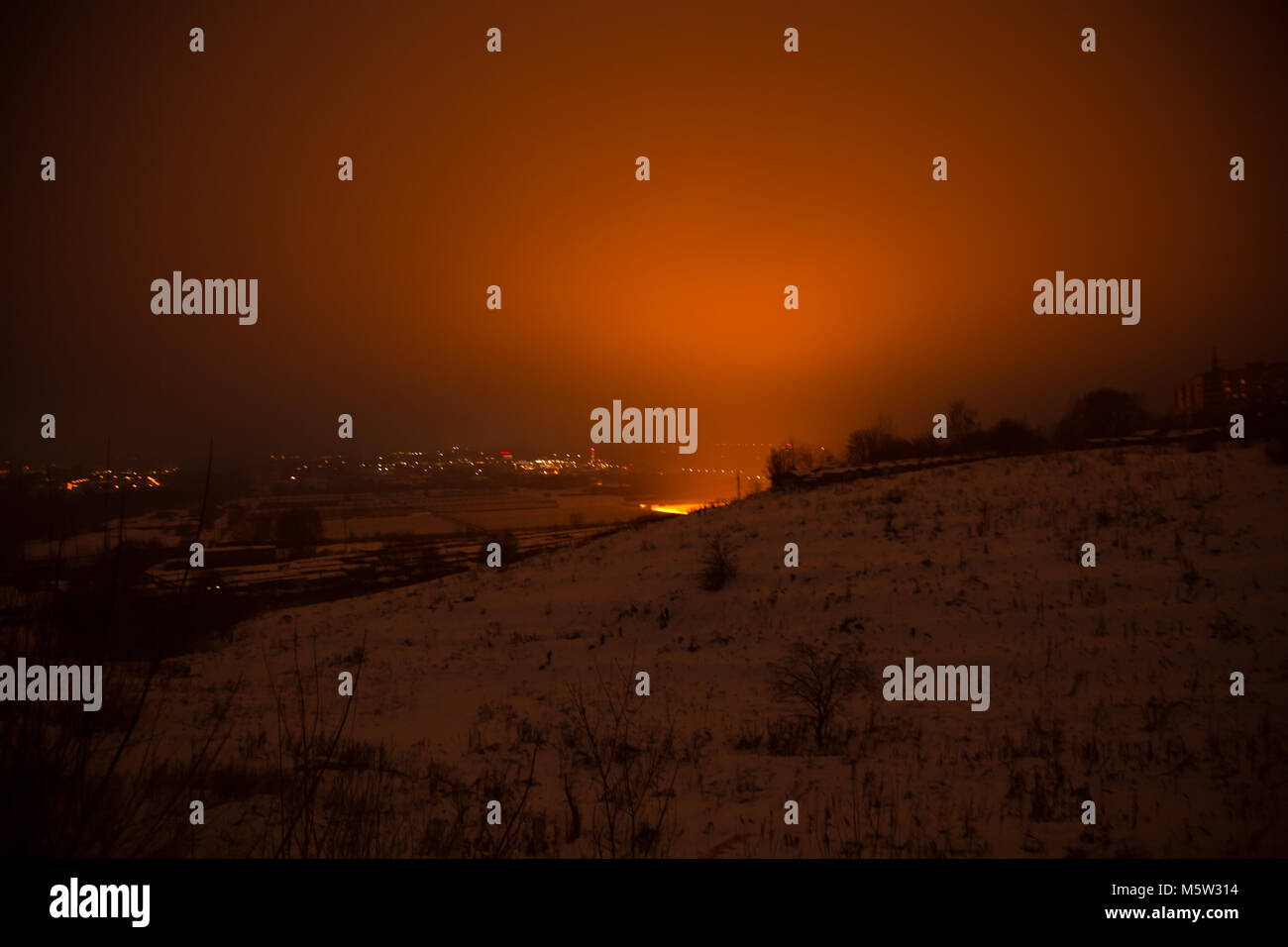 Winter night snowy hills orange sky background Stock Photo