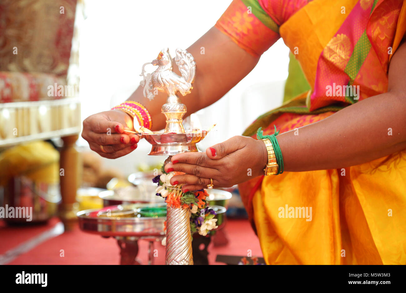 south Indian brass oil lamp with people stating the lighting on lamp