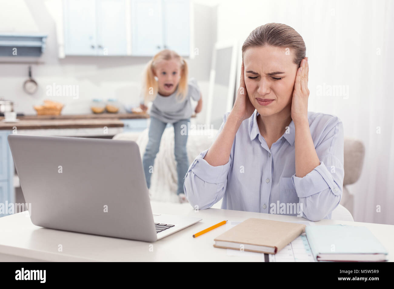 Stressful single mother obstructing from kids screaming Stock Photo