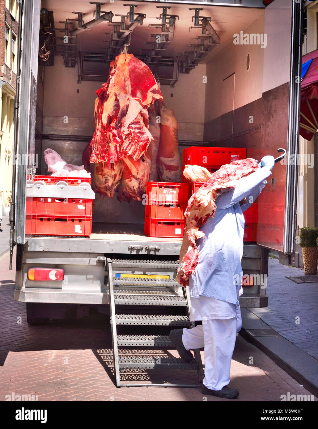 Food delivery of raw beef or pork, half beef in a cooling truck. Fresh red meat, buttery or slaughter house theme. Meat transporter, food industry. Stock Photo