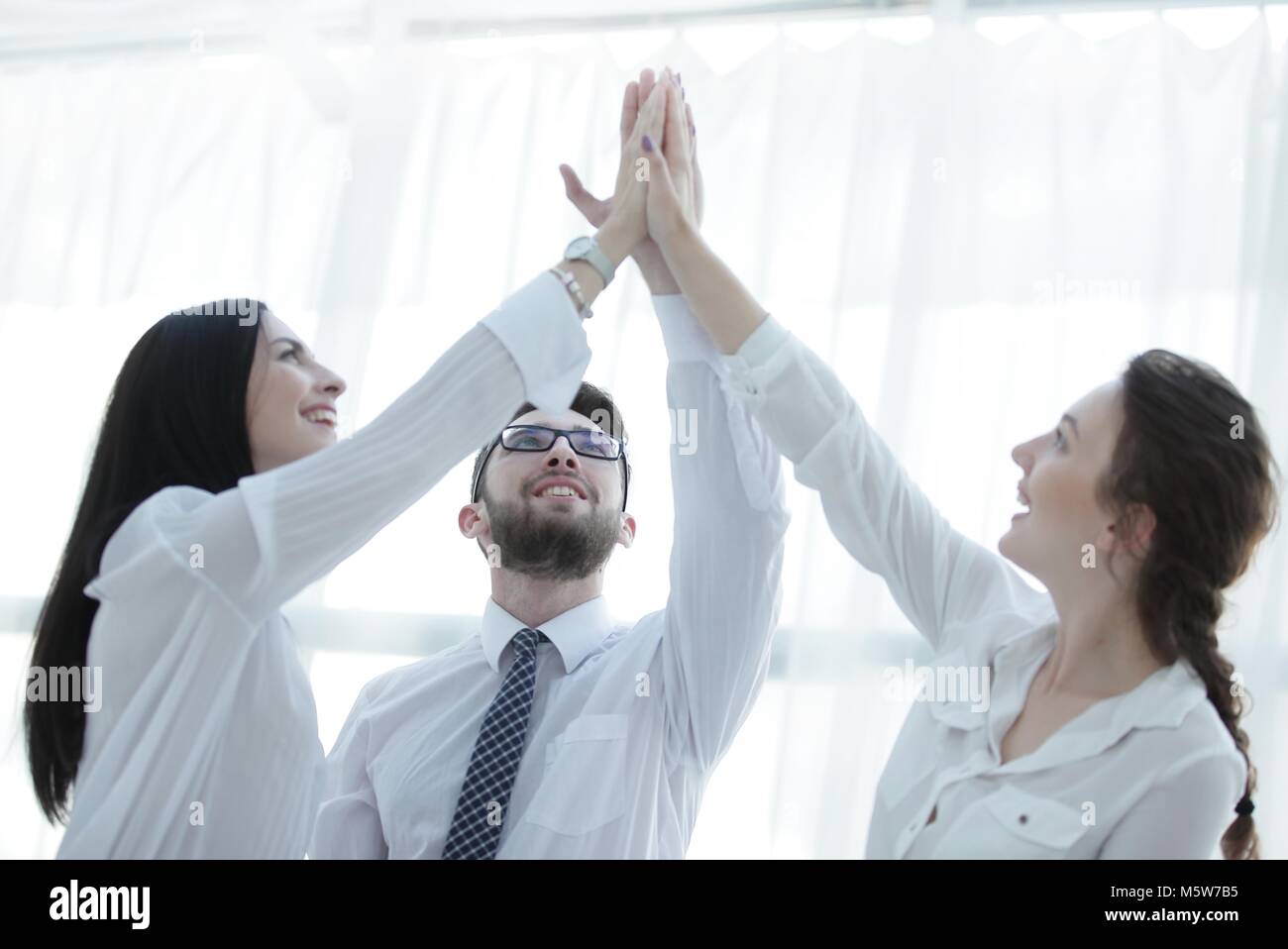 happy colleagues giving each other a high five Stock Photo - Alamy