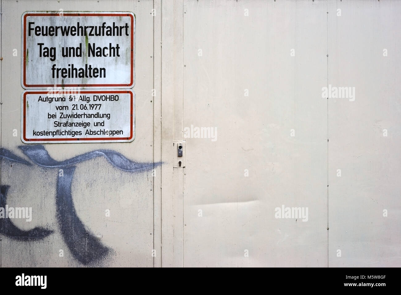 A scribbled fireproof steel door of a shopping mall with a warning sign, keeping firefighters accessible. Stock Photo