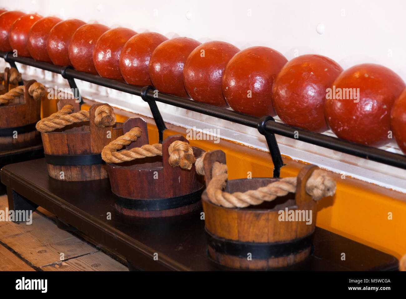 Cannonball / cannonballs / cannon ball / balls / in ammunition rack, & wooden pails to carry cooling water to the guns, HMS Warrior Portsmouth UK Stock Photo