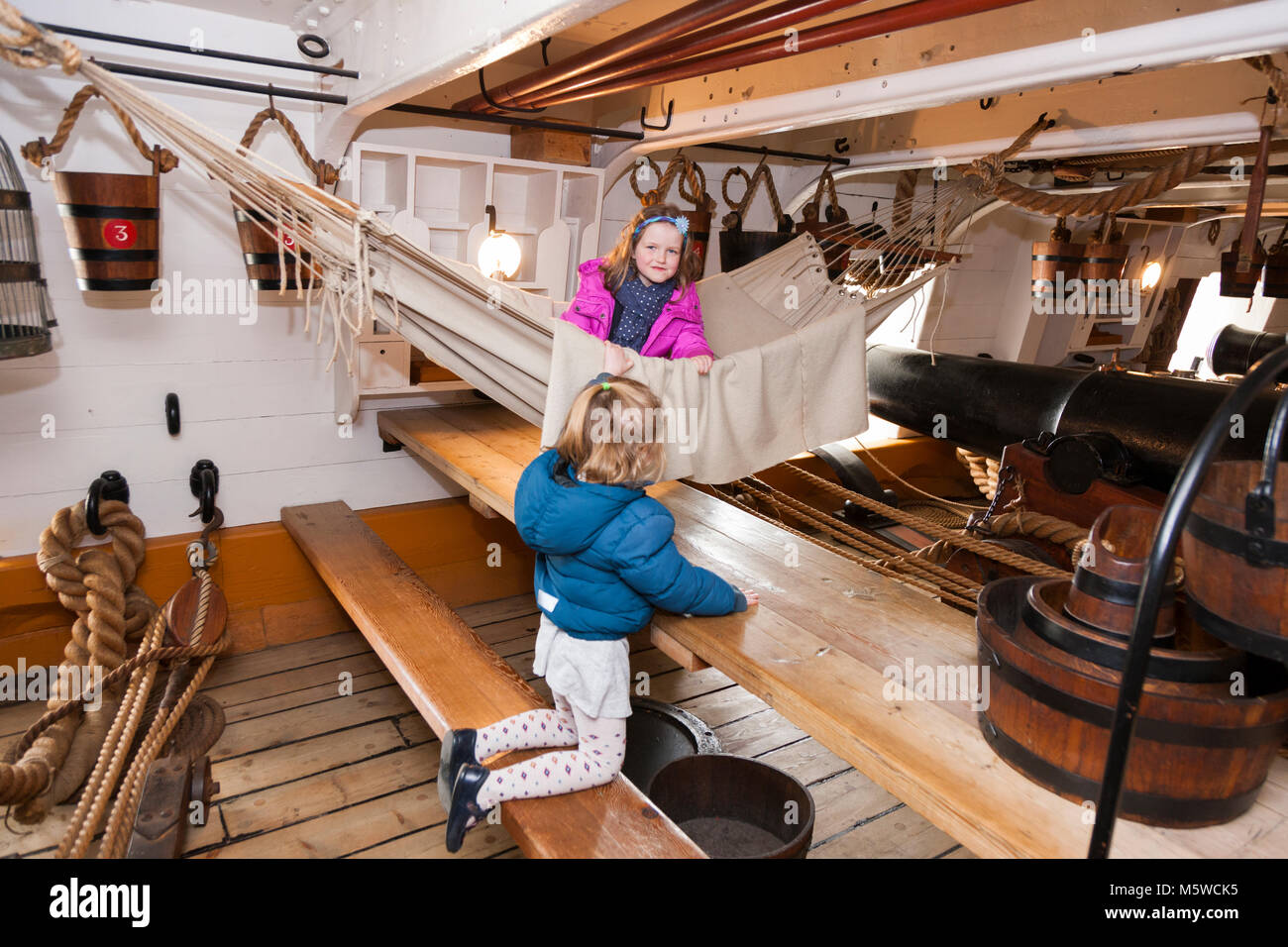 Tourist children play on hammock slung between 68 Pounder Carriage Guns