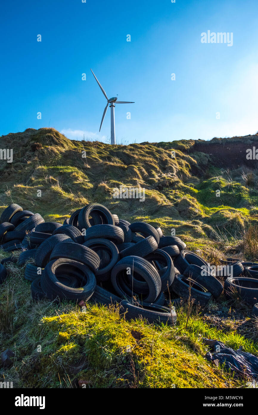 Fly tipping, dumped tyres with renewable energy image of wind turbine Stock Photo