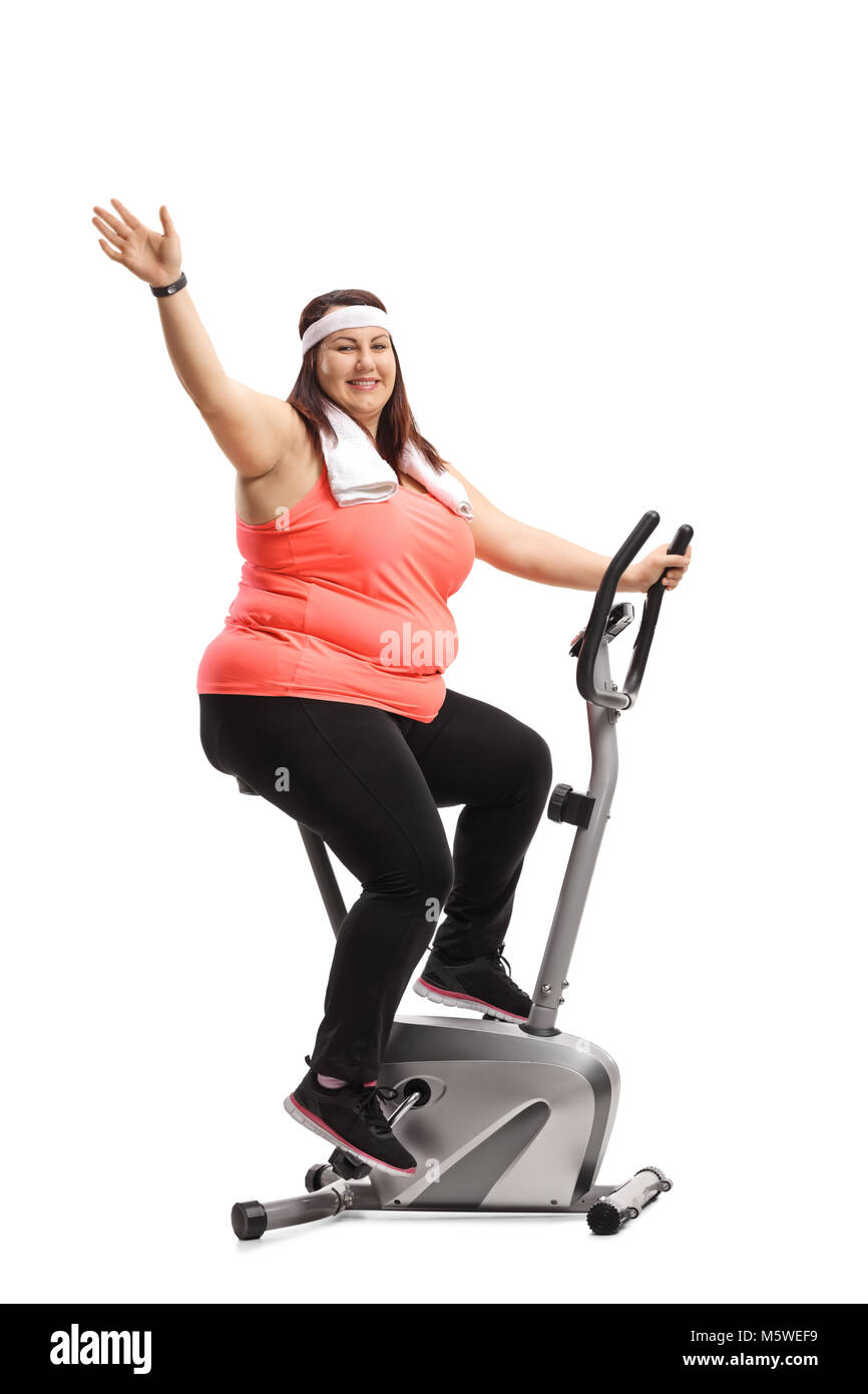 Overweight woman working out on an exercise bike and waving at the