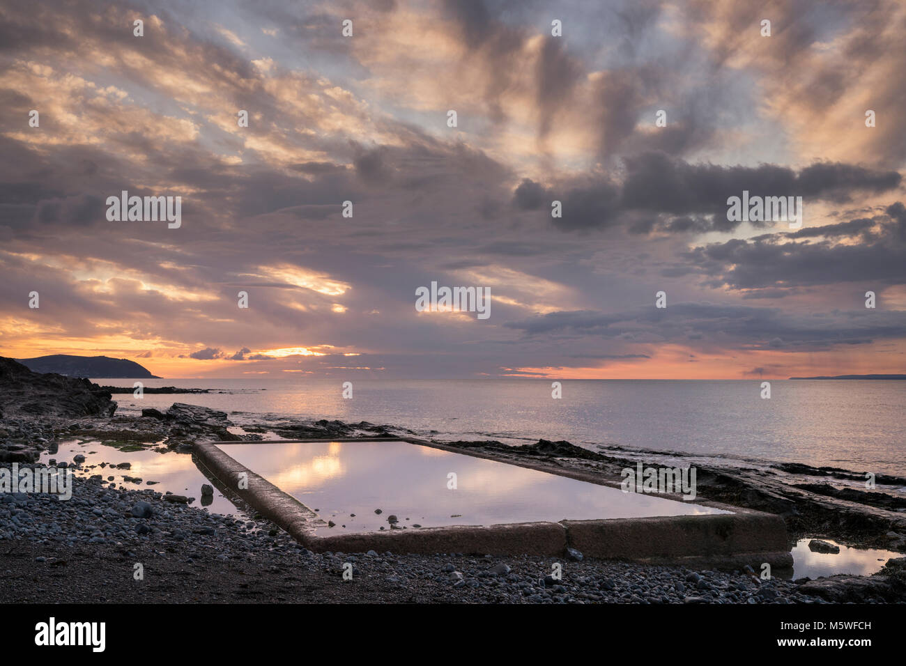 The seawater tidal pool at Watchet in Somerset, England on a summer evening at sunset looking east towards Minehead. Stock Photo