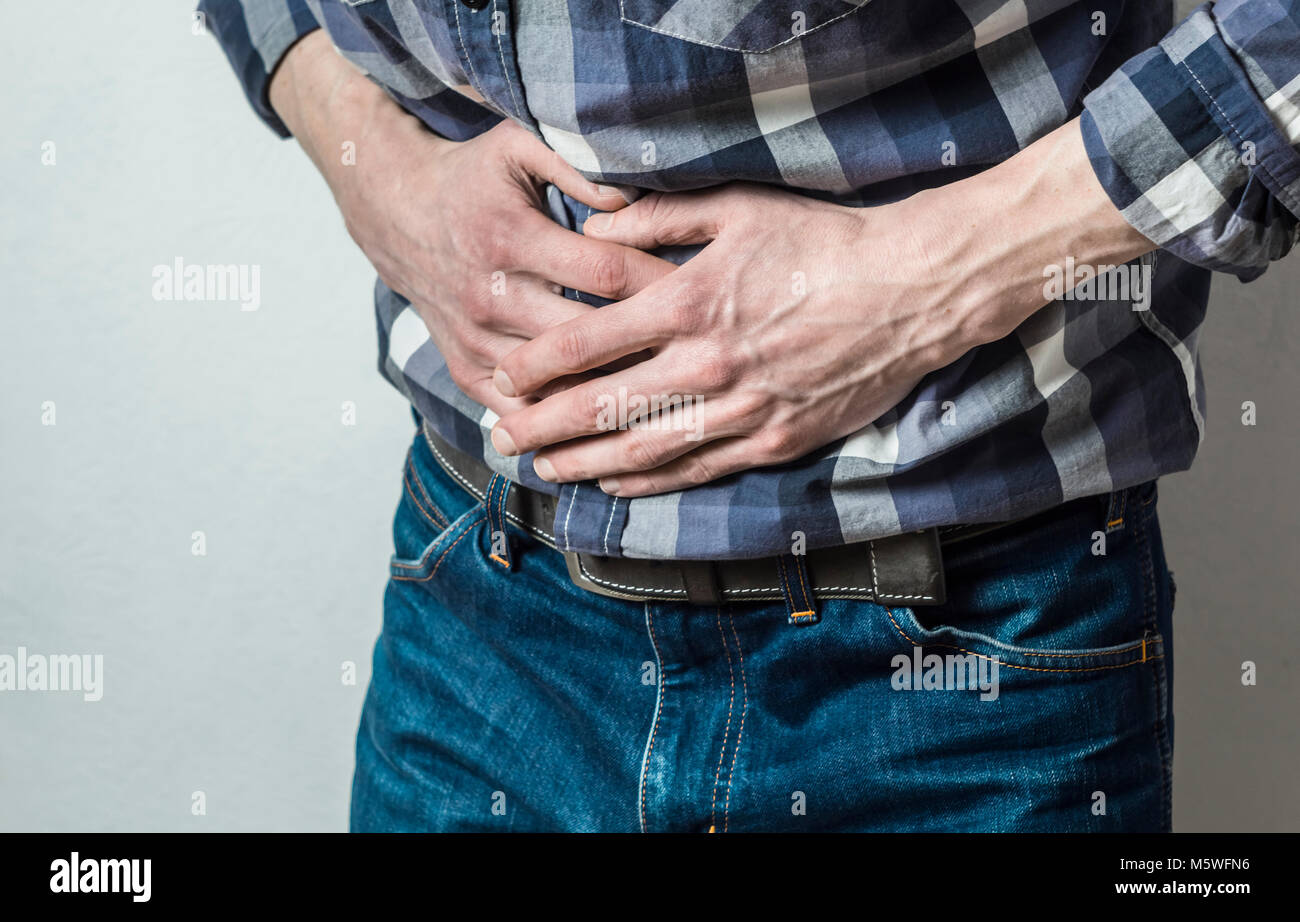 The man holds on to his stomach. Abdominal pain. Diarrhea. Spasm. Stock Photo