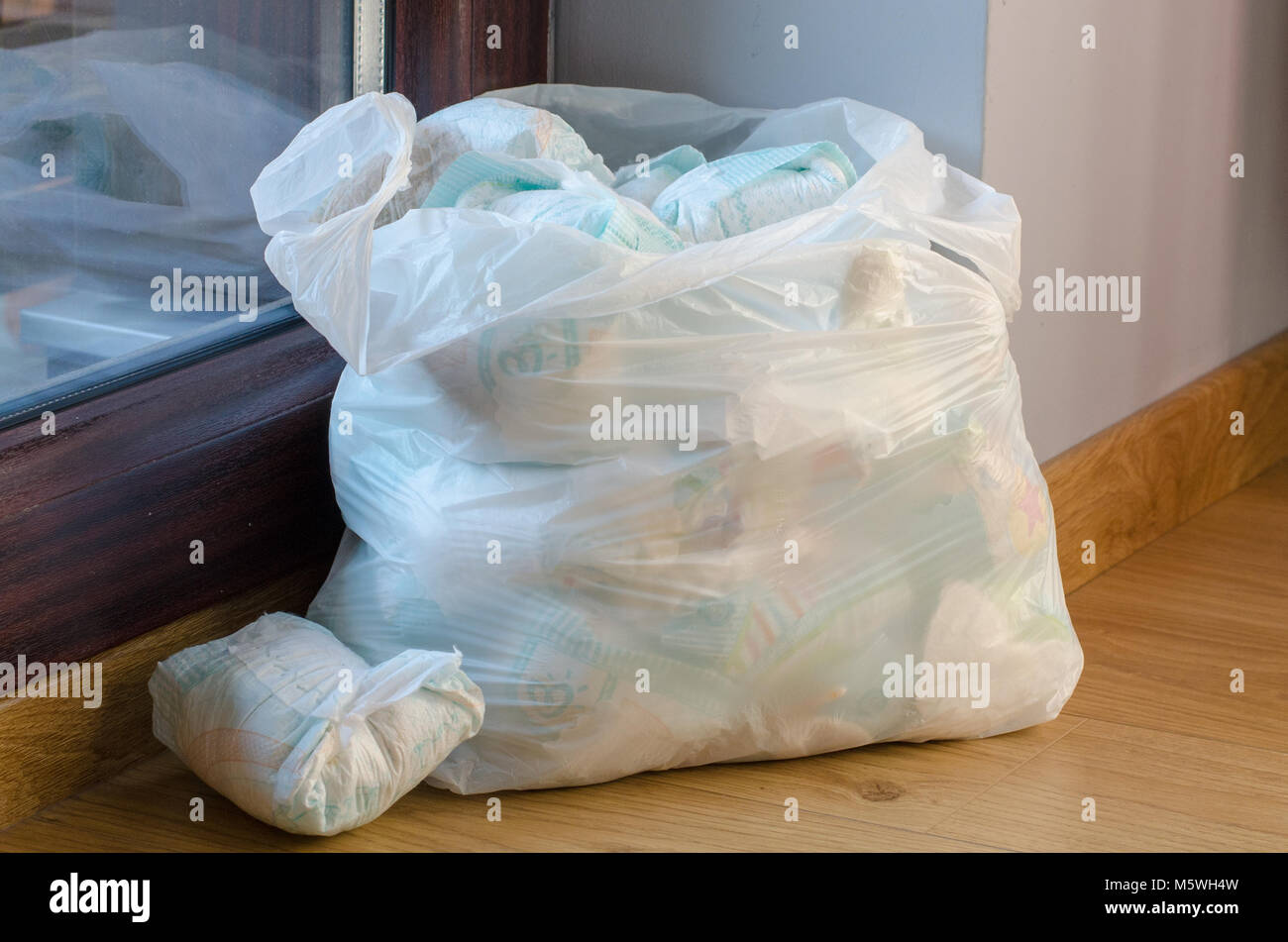 a bag full of dirty baby's   diapers standing on the floor side point view Stock Photo