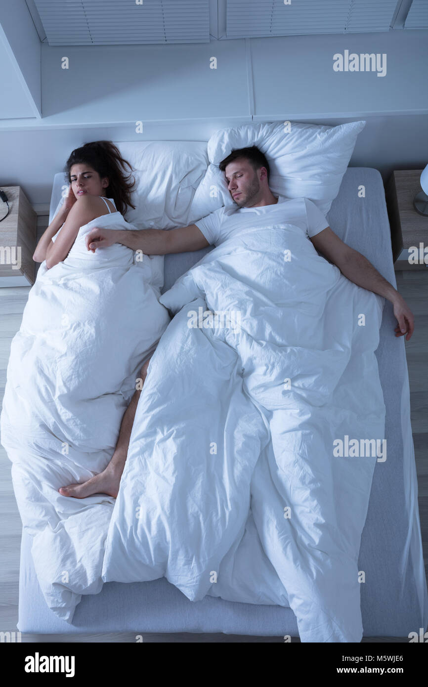 Elevated View Of Young Couple Sleeping On Bed At Home Stock Photo