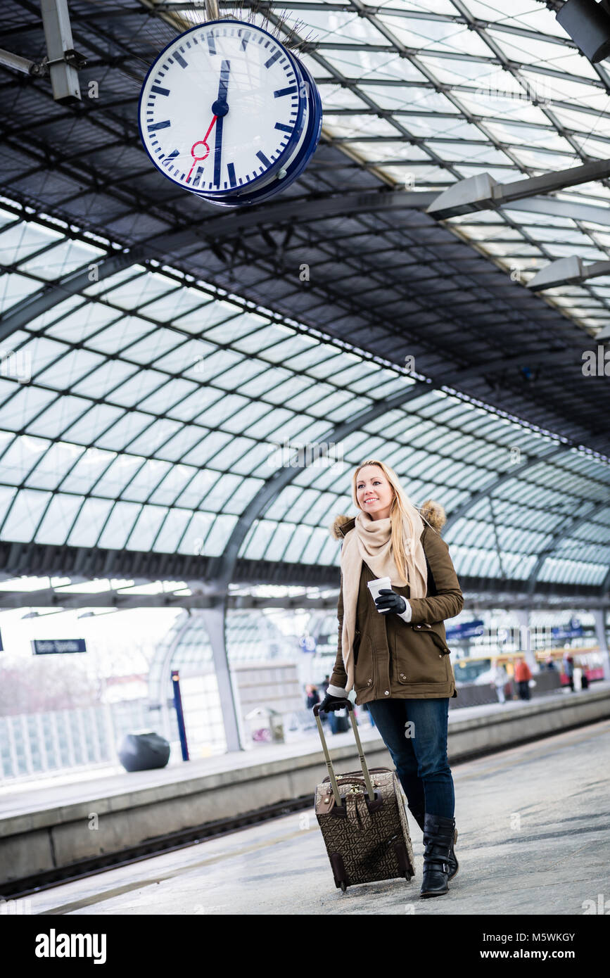 Woman looking at clock in train station as her train has a delay Stock Photo