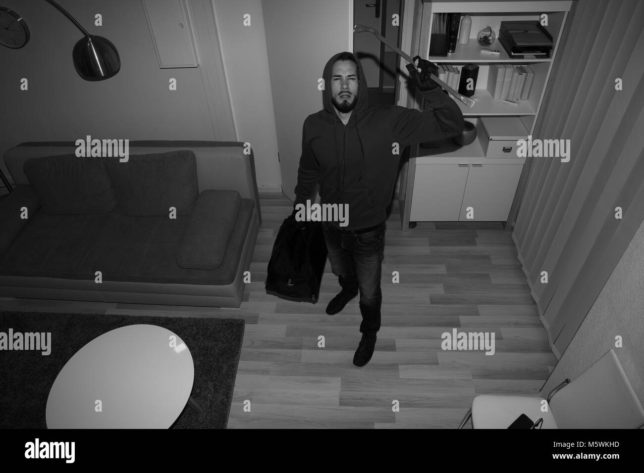 High Angle View Of A Robber Breaking CCTV Camera In Vacant House Stock Photo