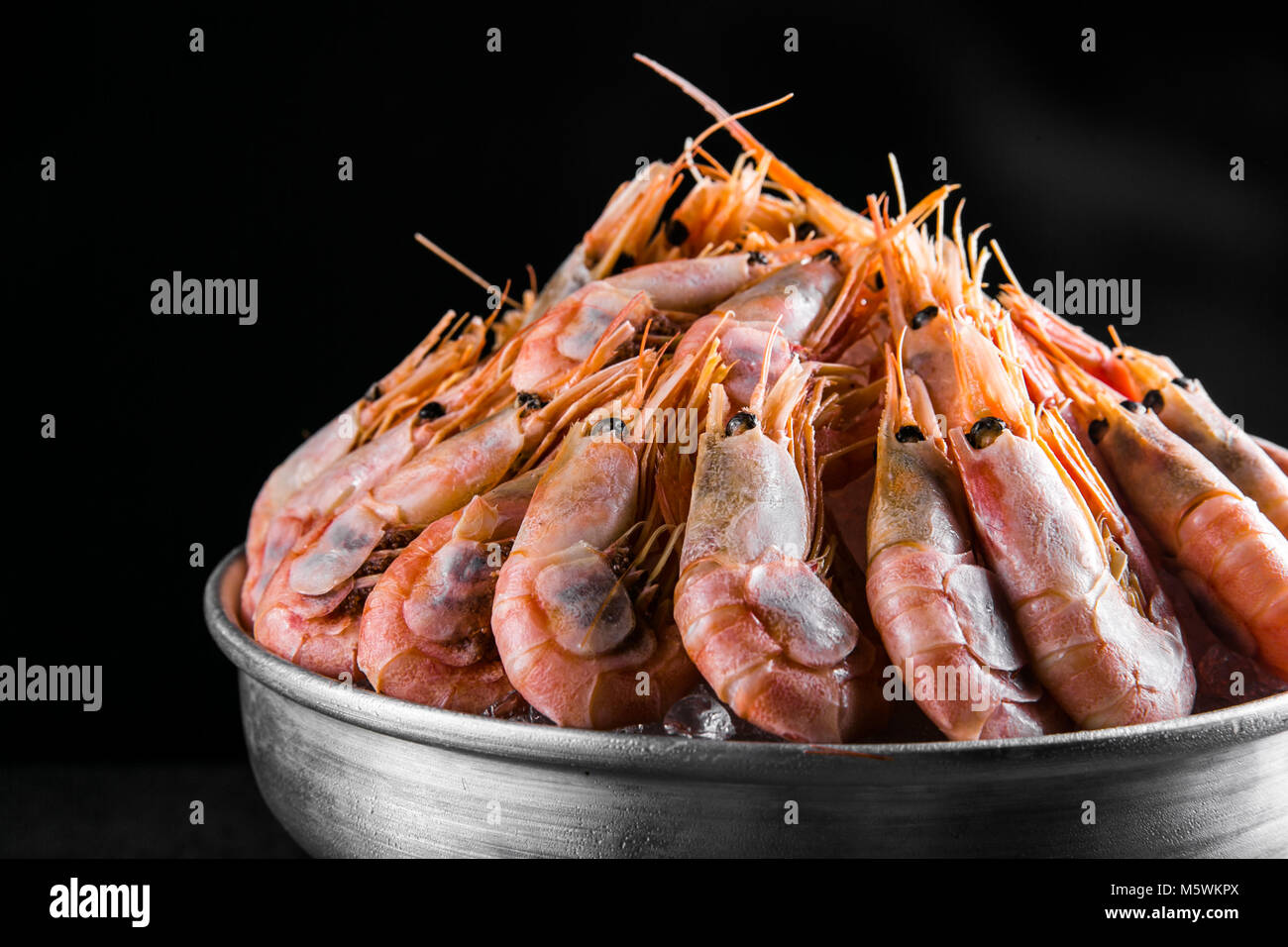 cooked Shrimps in a metal bucket on a dark background Stock Photo