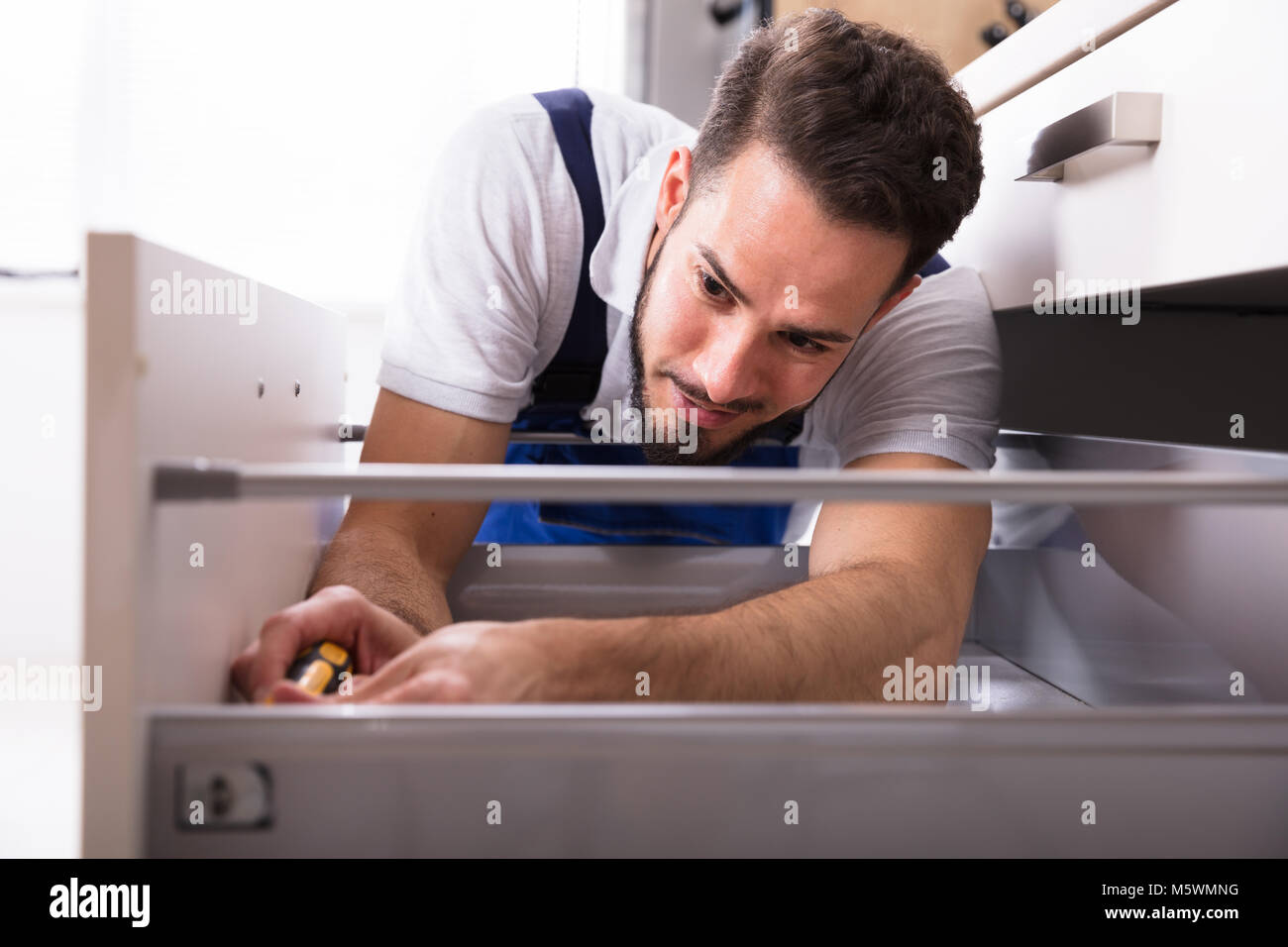 Close-up Of A Young Male Carpenter Installing Drawer With Screwdriver Stock Photo