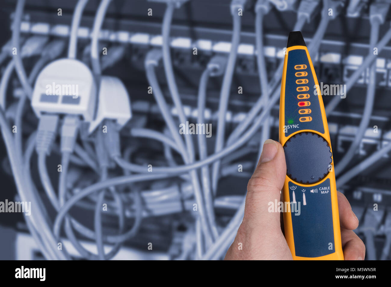 Measurement a cables connected in patch panels of rack case. Detail of expert's hand holding the probe to detect problems of structured cabling. Stock Photo