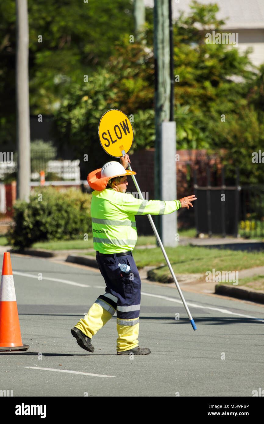 A man directs traffic with stop and slow sign at roadworks. Stock Photo