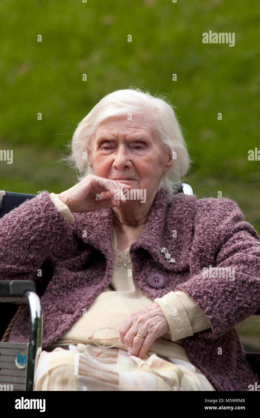 elderly lady with dementia sitting in wheelchair in park Stock Photo