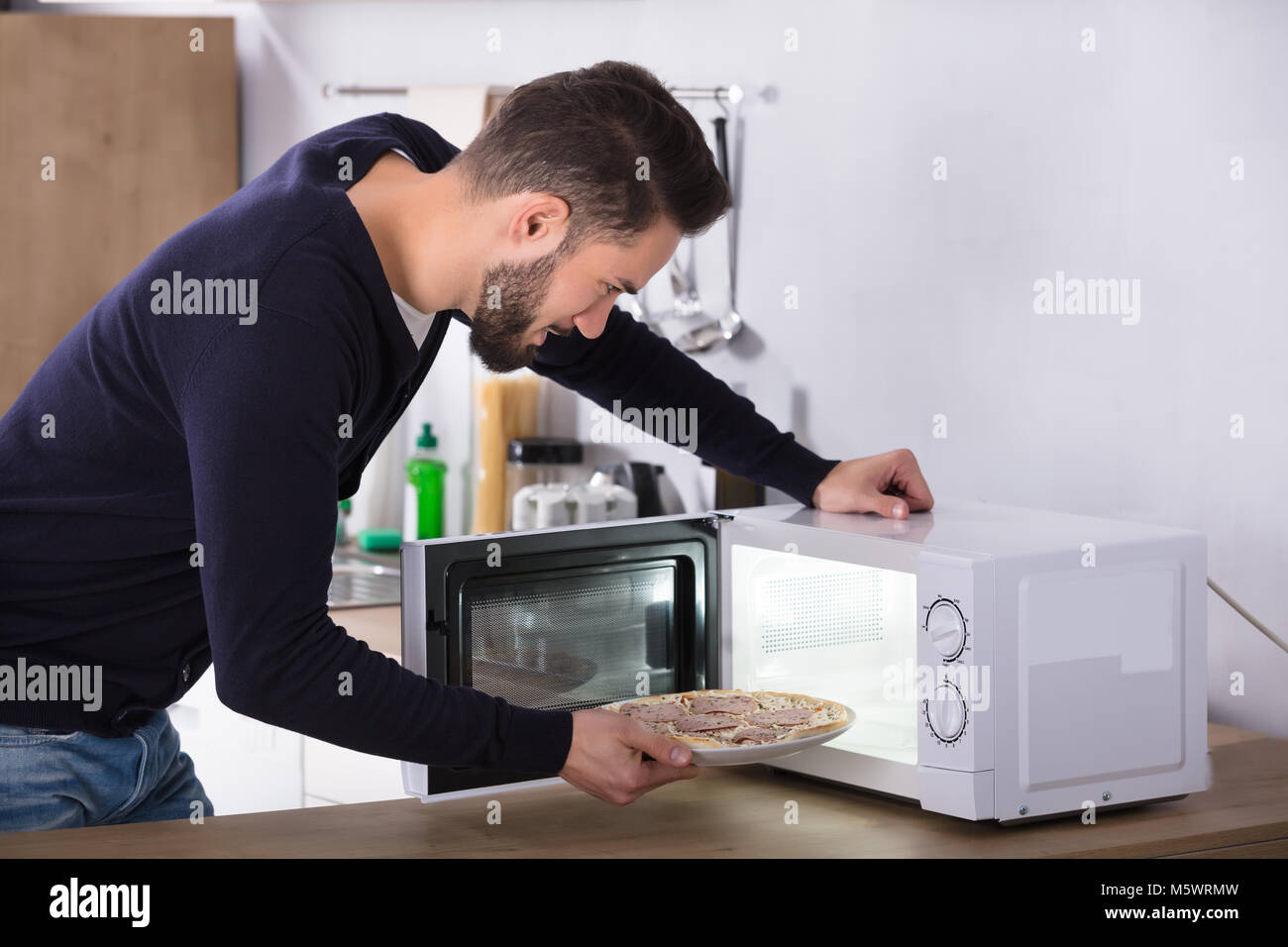 Side View Of A Young Man Baking Pizza In Microwave Oven Stock Photo Alamy