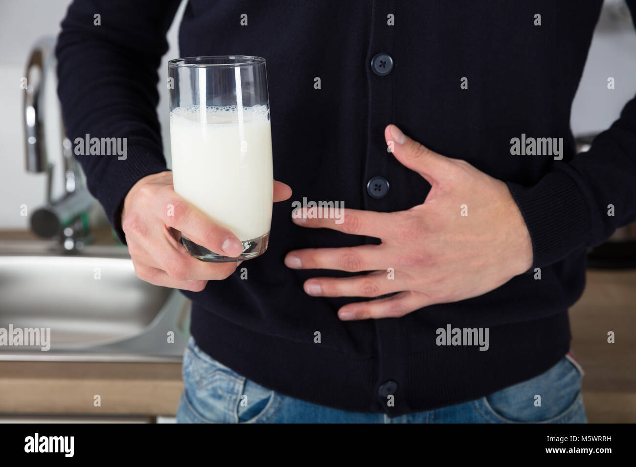 Mid Section View Of A Man With Stomach Pain Holding Glass Of Milk Stock